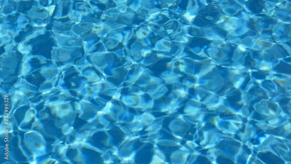 Blue turquoise pool water. Ripples lit up by the sun. Tiles visible below.