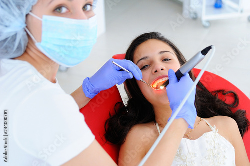 Young beautiful girl in dental office. Children's dentist examines teeth to a child.