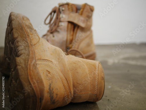 worn out work boots with zip and laces, light brown coloured, on rough concrete floor