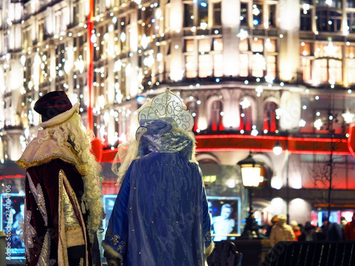 Santa Claus or Father Frost and Snow Maiden on the background of the festive night city. Celebration of New Year in Moscow, Russia