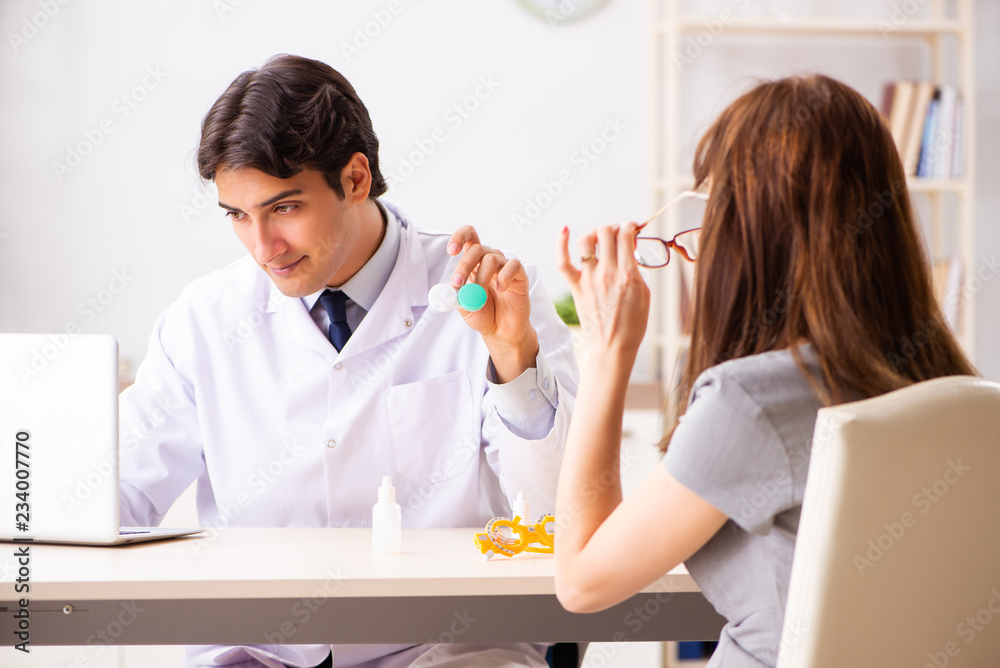 Fototapeta premium Young woman visiting male doctor ophthalmologist in hospital