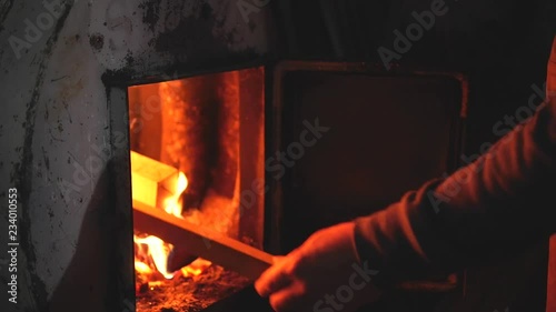 man throws wood in the stove