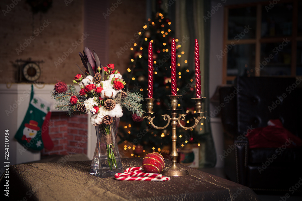 Christmas composition of a bouquet of an old candlestick on the background of a Christmas tree with a garland