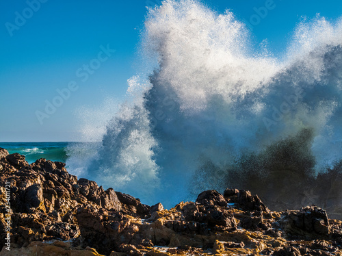 Large wave exploding over rocks