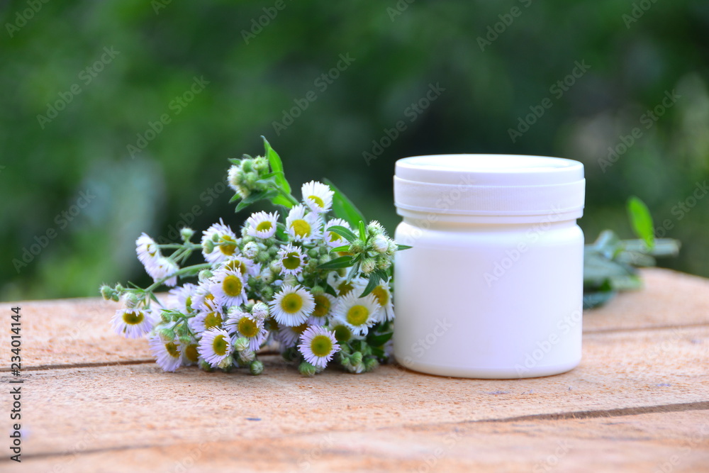Can for ointment in nature with chamomile flowers