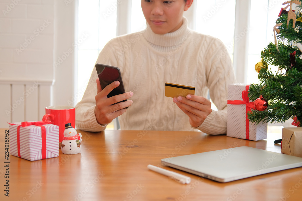man holding credit card & smart phone for online shopping. male buyer buying christmas gift on internet. xmas new year holiday celebration man holding credit card & smart phone for online shopping. male buyer buying christmas gift on internet. xmas new year holiday celebration