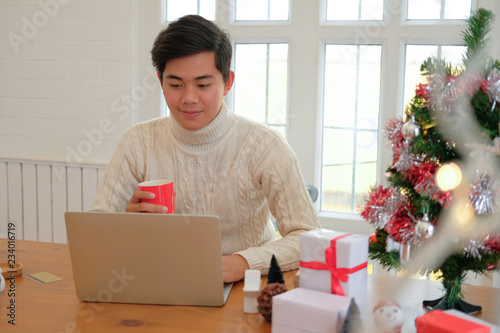 man holding coffee cup & using computer at home during christmas. xmas new year celebration © 88studio