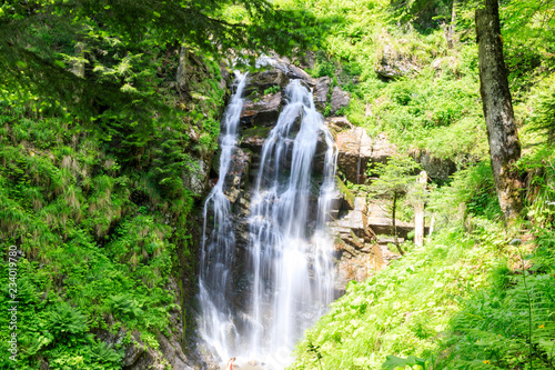 A valley with a waterfall in Mountains near the ski resort in tropical forest. Russian nature near Sochi, Caucasus Mountains.