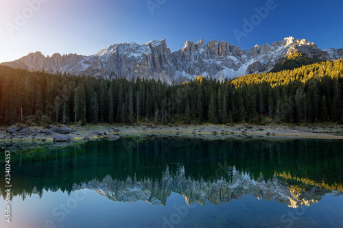 Beautiful sunrise at Carezza lake with light hitting the peaks, Dolomites, Italy © radu79