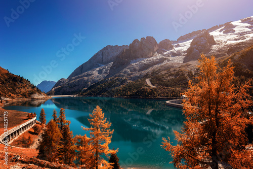 Fototapeta Naklejka Na Ścianę i Meble -  Beautiful autum colors at Fedaia lake with Marmolada peaks covered by ice, Dolomites, Italy