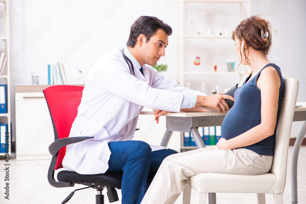 Young doctor checking pregnant woman's blood pressure Young doctor checking pregnant woman's blood pressure