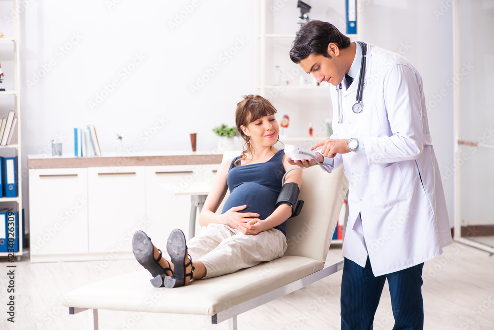 Young doctor checking pregnant woman's blood pressure Young doctor checking pregnant woman's blood pressure