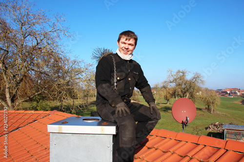 A chimney sweeper sitting on a flue on top of the roof
