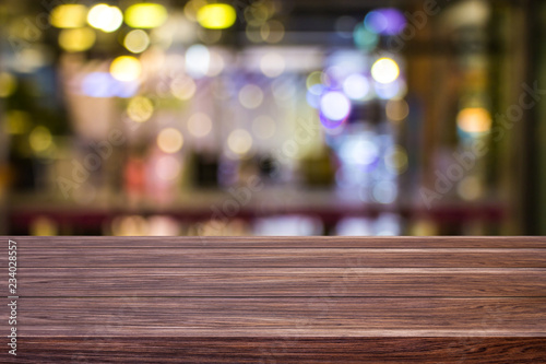 Blur cafe restaurant or coffee shop empty of dark wood table with blurred light gold bokeh abstract background for montage product display or design.