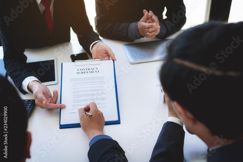 closeup hand of business man signing contract document and handshaking after finished meeting.