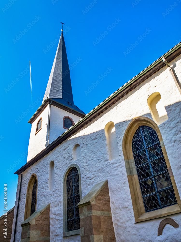 Exterior side partial view of the old Church of St. Lawrence in Diekirch, Luxembourg with a contrail in the sky