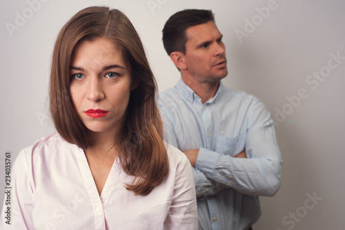 Upset caucasian man crossed folding arms looking to his left side dressed in blue shirt and woman in white blouse having difficulties and problems in relationships. Shoot on white background