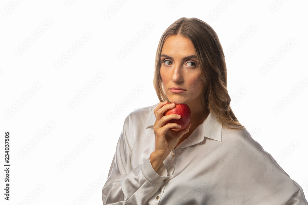 A girl with long blond hair is holding an apple A girl with long blond hair is holding an apple