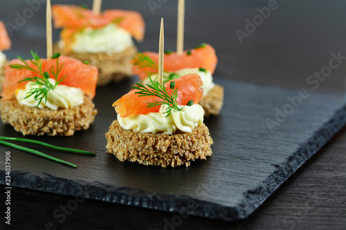 Smoked salmon canapes with cheese cream and dill on brown bread