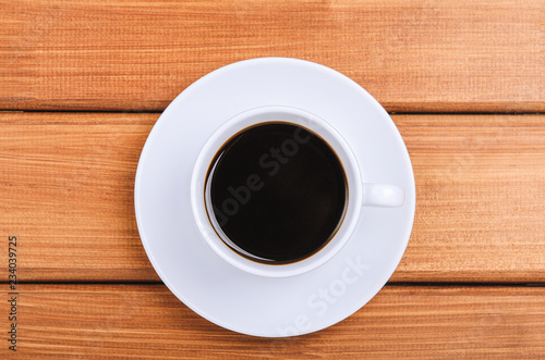 A cup of hot coffee on wooden background. Copy space, top view, flat lay