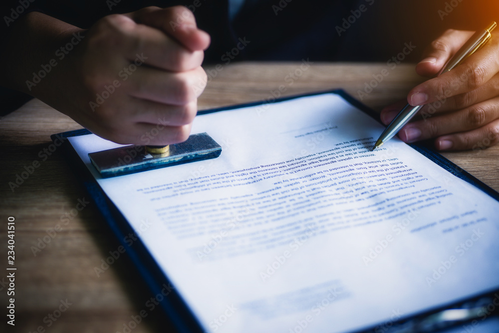 Business woman or lawyer sitting with hand holding stamp approve important contract in office. Legal law and justice concept. Business woman or lawyer sitting with hand holding stamp approve important contract in office. Legal law and justice concept.