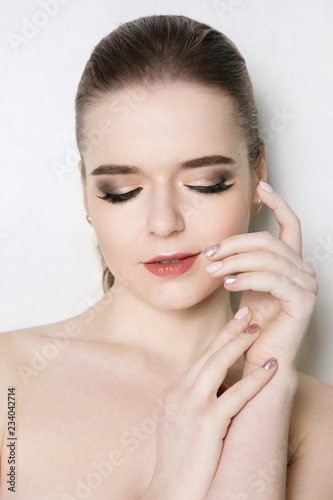 Young girl with professional make-up and pink manicure on a white background