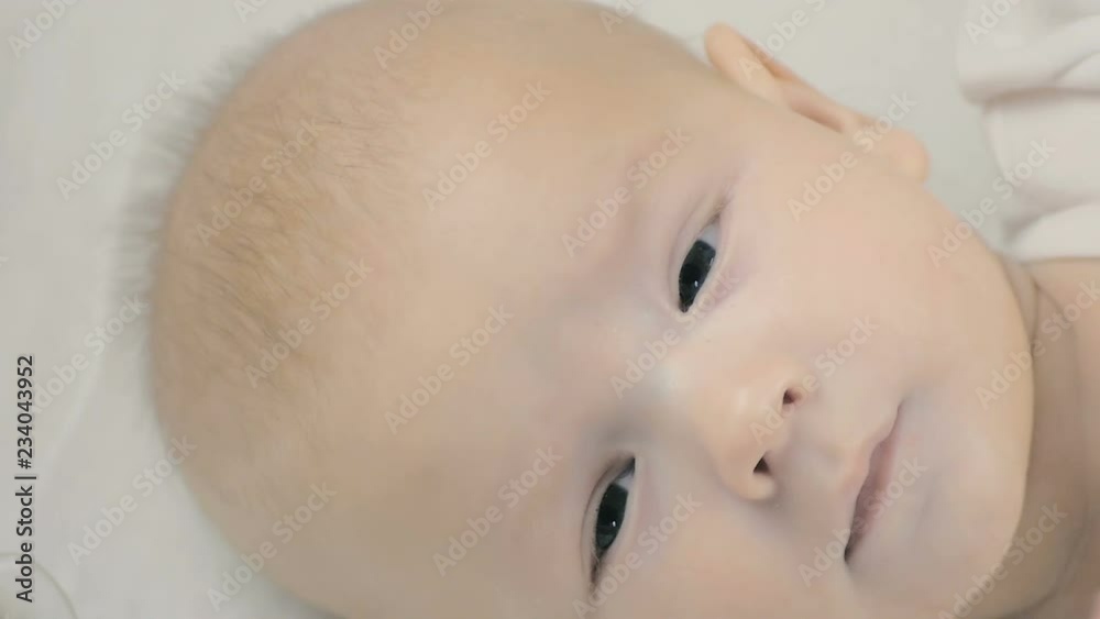 Close-up of a newborn baby lying on his bed and looking at the camera. Close-up of a newborn baby lying on his bed and looking at the camera.