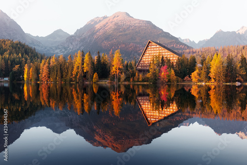 Fototapeta Naklejka Na Ścianę i Meble -  Picturesque autumn view of lake Strbske pleso in High Tatras National Park, Slovakia. Clear water with reflections of orange larch and high mountains on background. Landscape photography
