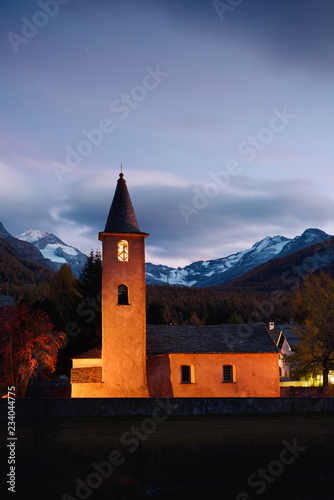 Christianity church on Sils village (near lake Sils) in Swiss Alps. Orange light on building and snowy mountains on background. Switzerland, Maloja region, Upper Engadine. Landscape photography