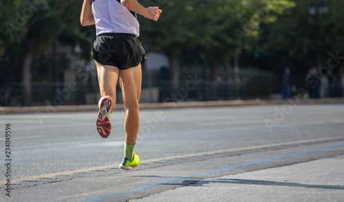 Running in the city roads. Young man runner, back view, blur background, copy space