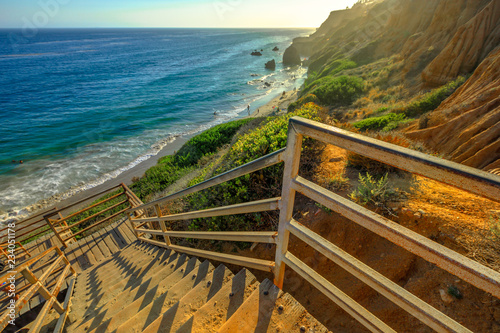 Scenic wooden stairway leading down to El Matador State Beach at sunlight. Pacific coast, California, United States. Pillars and rock formations of most photographed Malibu beach, popular spot shot. photo