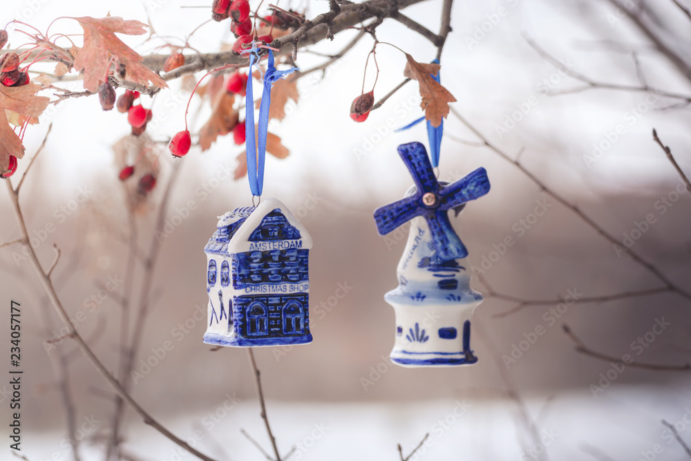 Blue ceramic Christmas toy bought in Amsterdam hangs on a branch