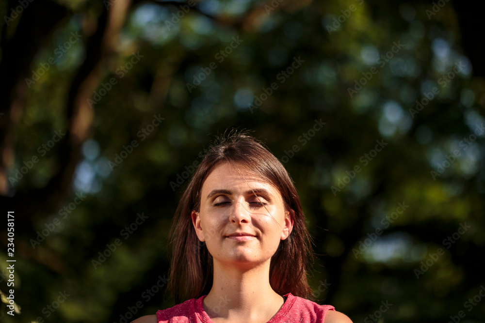 portrait of positive young woman meditating in park portrait of positive young woman meditating in park