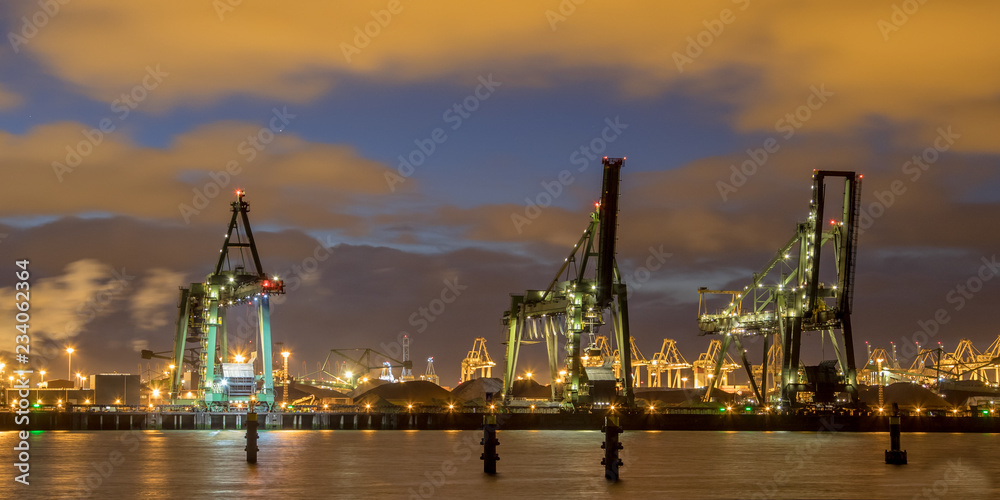 Industrial landscape with Harbor quay and loading cranes at night