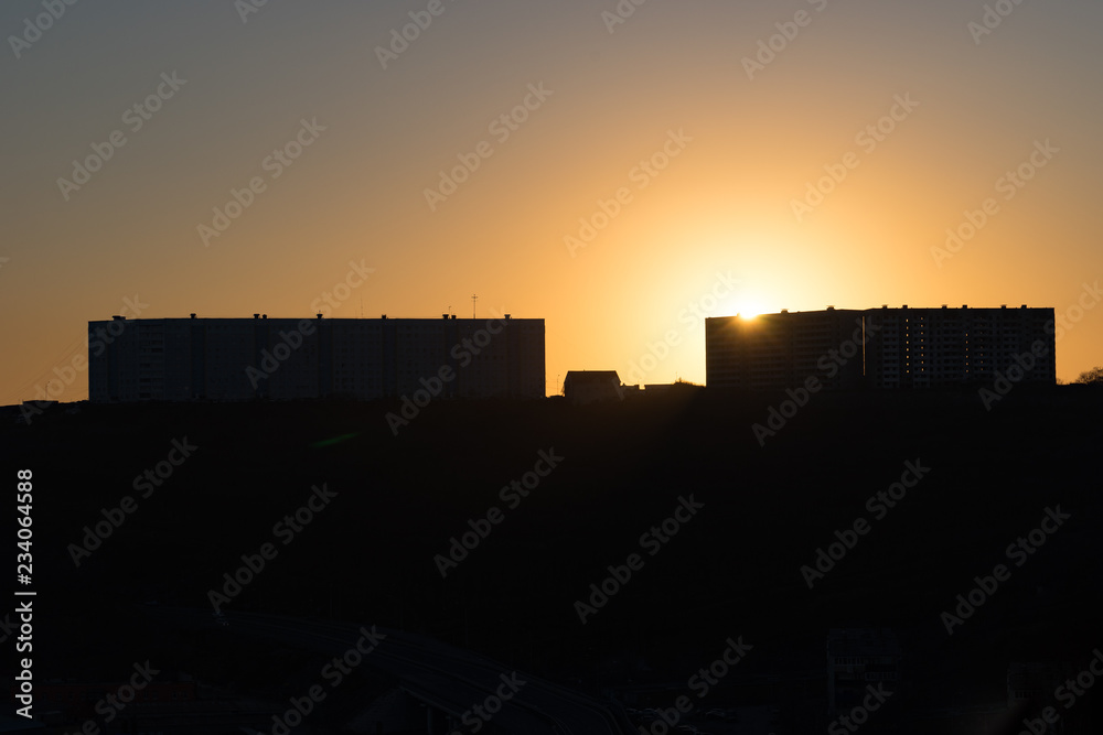 urban landscape with silhouettes of high-rise buildings in the background light of the sunset.