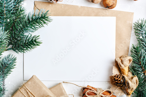 Merry Christmas and happy New year. Mockup with postcard and branches of a Christmas tree on white background. Background with copy space. Top view. Christmas background. Horizontal.