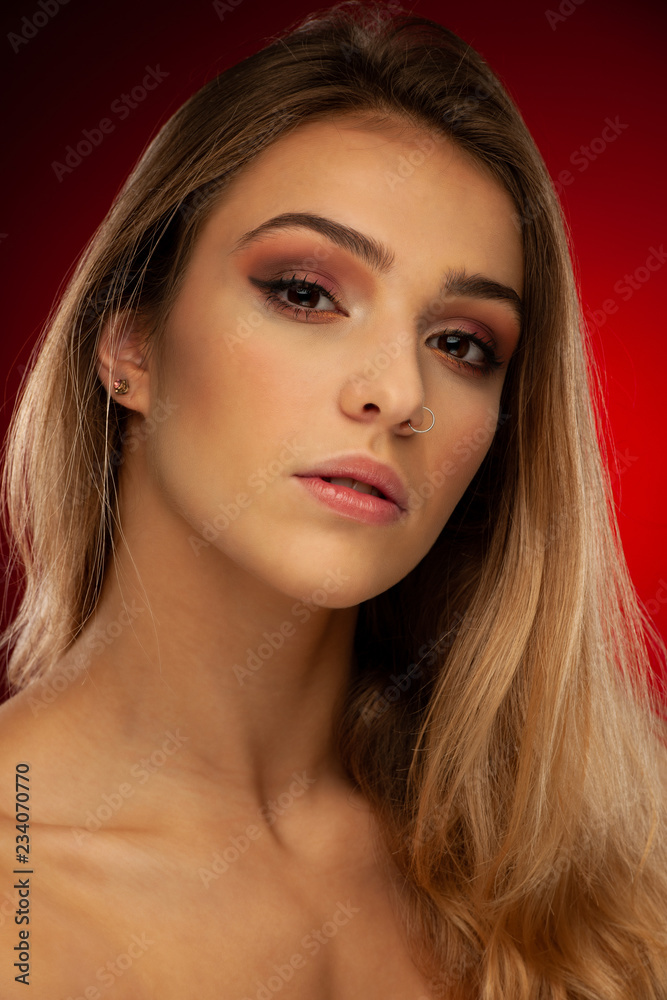 Beauty portrait of a beautiful young woman with brown long hair over dark red background Beauty portrait of a beautiful young woman with brown long hair over dark red background