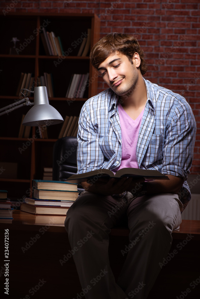 Young handsome student preparing for exams at night 