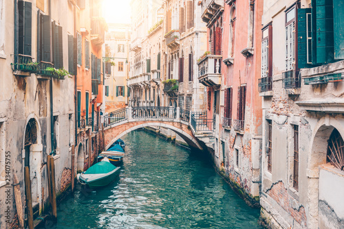 Narrow canal with boat and bridge in Venice, Italy. Architecture and landmark of Venice. Cozy cityscape of Venice.