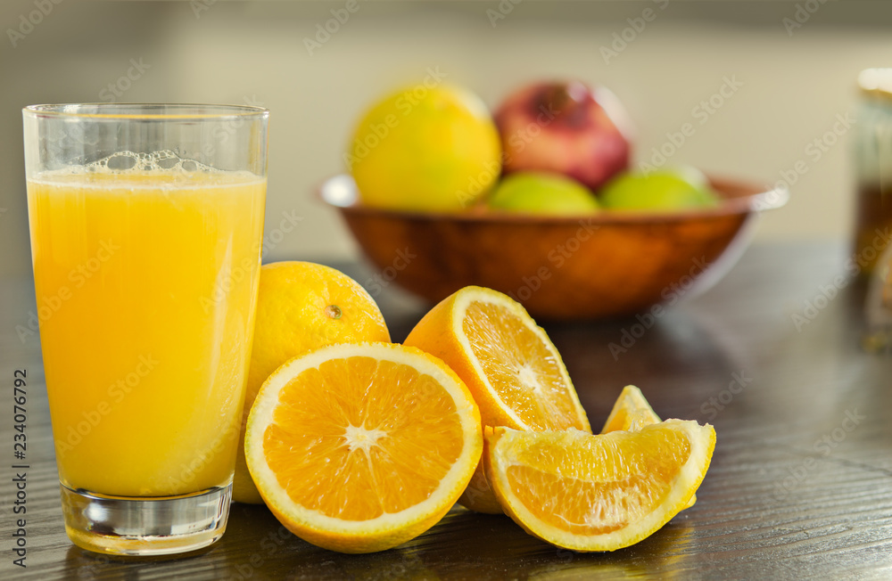 Glass of freshly squeezed orange juice with bowl of fruits on the background. Glass of freshly squeezed orange juice with bowl of fruits on the background.