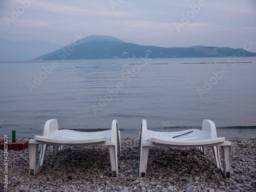 Two empty plastic chaise lounge on sea side at the end of season side view © yuakimov