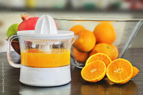 Juicer with freshly squeezed  orange juice and whole and sliced oranges. photo