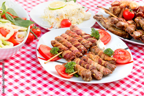Grilled kebabs, rolled kebab with bacon and salad