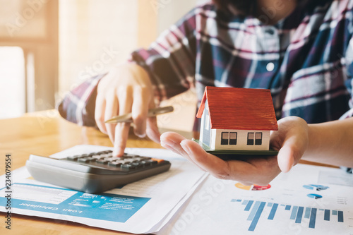 woman calculating budget before signing real estate project contract with house model at the table in the home