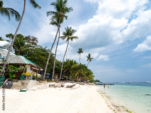 Amazing tropical beach background from Alona Beach at Panglao Bohol island with Beach chairs on the white sand beach with cloudy blue sky and palm trees. Philippines, november, 2018 photo