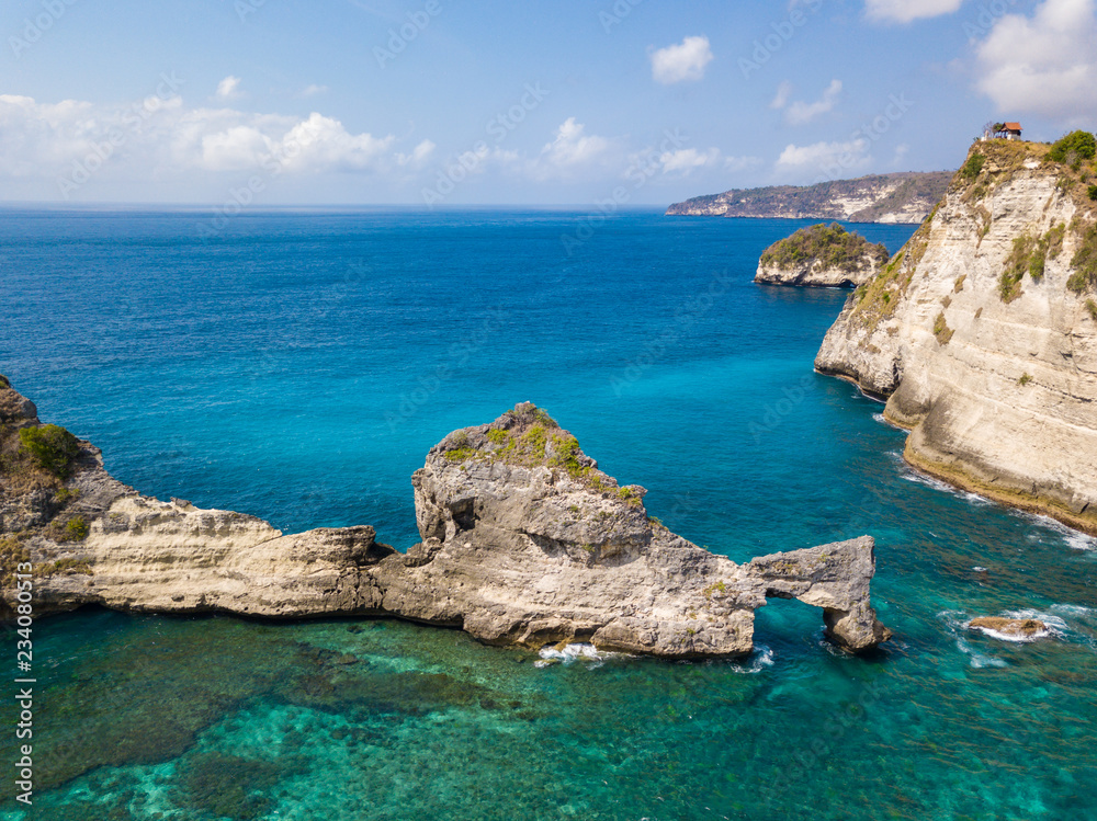 Fototapeta premium Aerial view to beautiful arched rock in ocean on Atuh beach. Photo from drone. Nusa Penida, Bali, Indonesia