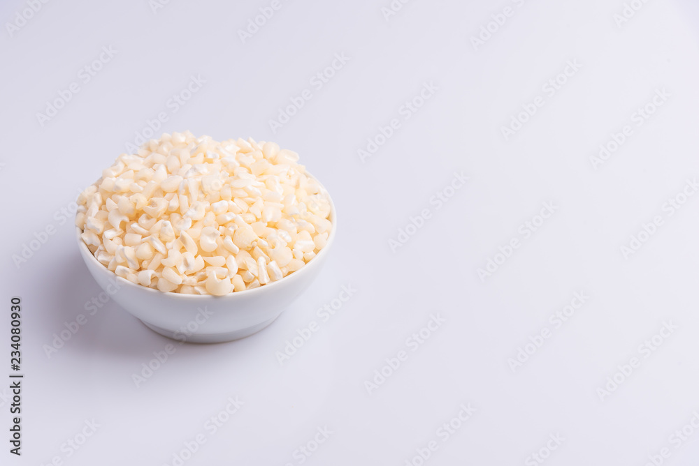 Dry uncooked white corn ingredient for Brazilian dessert sweet canjica / mungunza, white background, isolated, soft light. Festa Junina Party Brazilian Culture Concept Image.