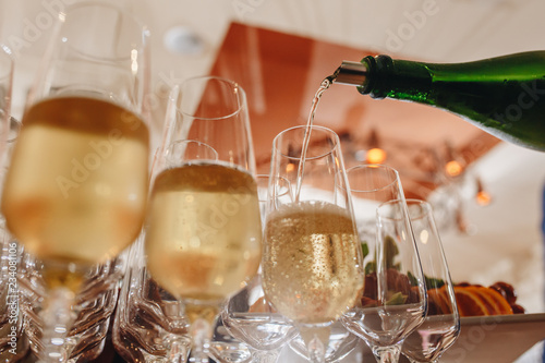 Sommelier pours champagne from a bottle into a glass at the table in the restaurant.
