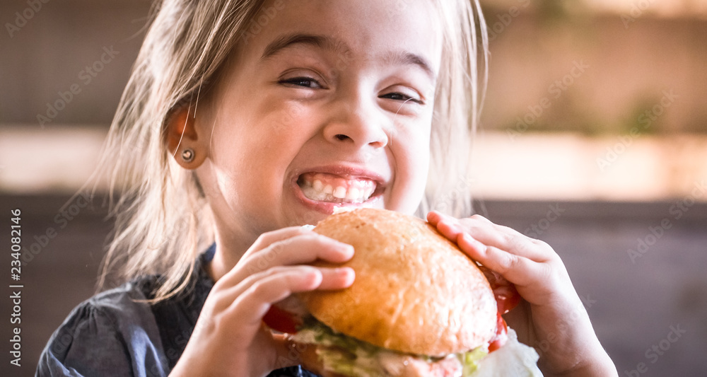 A little girl eats a sandwich in a cafe A little girl eats a sandwich in a cafe