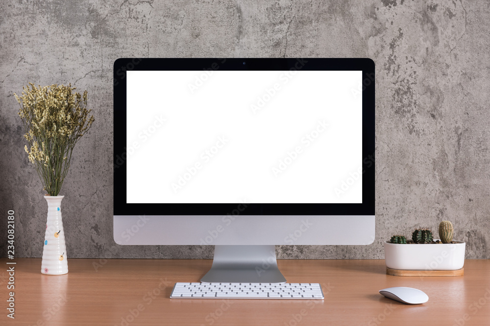 Blank screen of all in one computer with dry flowers and cactus vase on raw concrete background Blank screen of all in one computer with dry flowers and cactus vase on raw concrete background